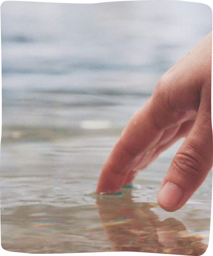 A hand reaching into clear river water at dawn